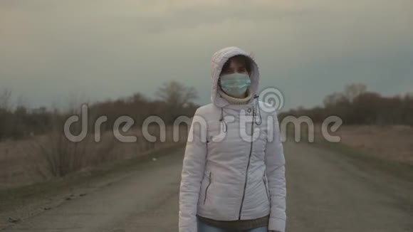 大流行冠状病毒女游客戴着防护医疗面具正在城外的路上行走防止视频的预览图
