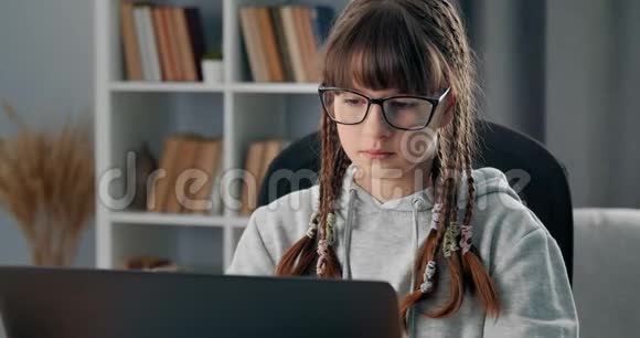 戴眼镜的女孩坐在家里用笔记本电脑学习视频的预览图