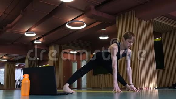 一个瑜伽教练从健身房在线上课他伸了一条腿劈开了一个年轻可爱的白人视频的预览图