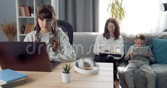 可爱的女学生坐在家里拿着笔记本电脑学习视频的预览图