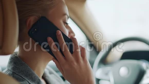 女性在方向盘后使用手机的背面视图女孩呼叫智能手机视频的预览图
