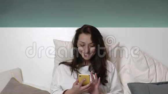快乐的白种人女人在床上用手机说话笑容满面视频的预览图