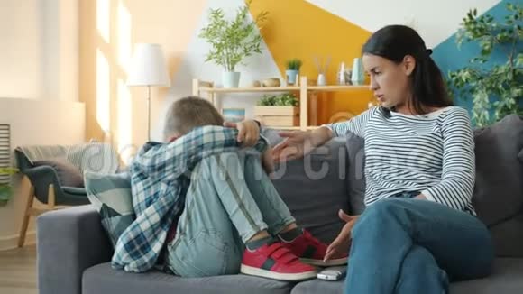 严厉的女人惩罚小儿子手指着坐在沙发上的孩子感觉很痛苦视频的预览图