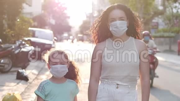 妈妈和女儿站在一条街上戴着CovidN1H1流行病的防护面具健康与安全概念视频的预览图