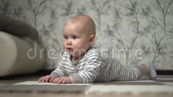 一个一岁的小孩子穿着条纹灰色工作服躺在地板上一个亚麻球卷起孩子开始玩视频的预览图