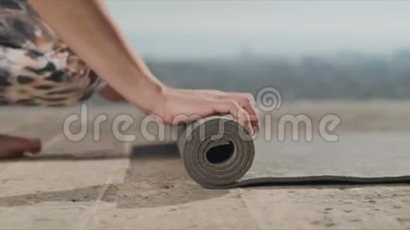 女子手在训练后卷起瑜伽垫户外女孩折叠健身垫视频的预览图