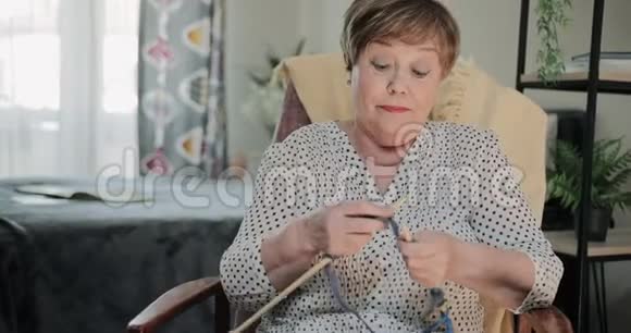 前景美丽的奶奶坐在椅子上家里有针织针快乐的老年女士视频的预览图