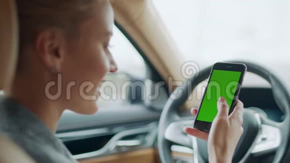 女商人带智能手机的汽车肖像带绿色屏幕手机的女人视频的预览图
