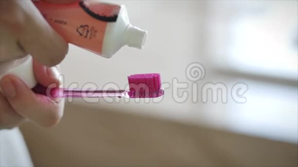 一只雌性的手把彩色牙膏挤到粉红色牙刷上现代浴室的口腔卫生特写镜头视频的预览图