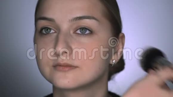 化妆师为美容工作室的年轻女性制作专业化妆化妆师用大的粉末视频的预览图