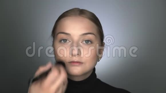 化妆师在美容工作室为年轻女性做专业化妆化妆师用大的粉末视频的预览图