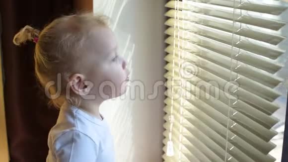 小女孩透过百叶窗向窗外望去视频的预览图