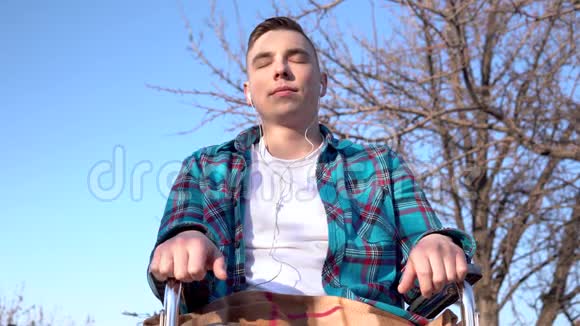坐轮椅的年轻人带着耳机天生残疾的人耳朵里戴着耳机视频的预览图