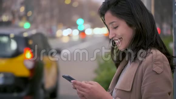 漂亮的年轻女人在夜里在路边等人接电话时用手机发短信视频的预览图