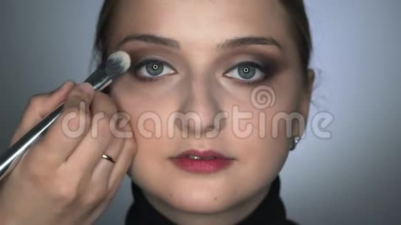 化妆师在美容工作室为年轻女性做专业化妆化妆师用刷子视频的预览图