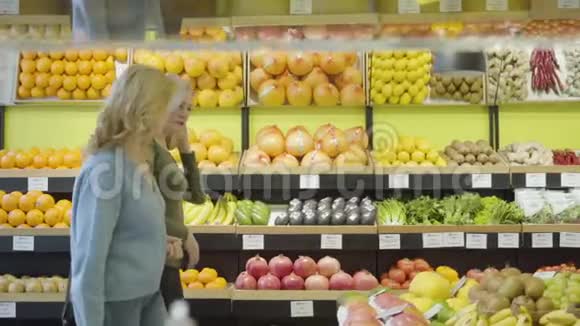 两个金发白种人家庭主妇在杂货店里一排排地散步和聊天严肃自信的女人选择视频的预览图