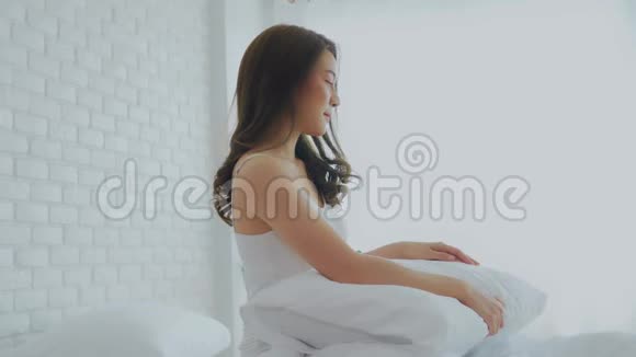 一幅美丽迷人的亚洲年轻女子的肖像早上醒来后微笑拥抱枕头视频的预览图