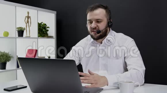 穿着正式西装戴着耳机在办公室外工作的年轻人手提电脑视频的预览图