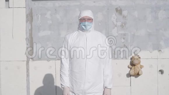 穿着白色安全套装面罩和防护眼镜的白人男孩站在墙的背景下视频的预览图