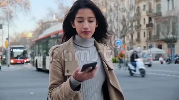 漂亮的年轻女人站在街上用手机说话背景中城市交通视频的预览图
