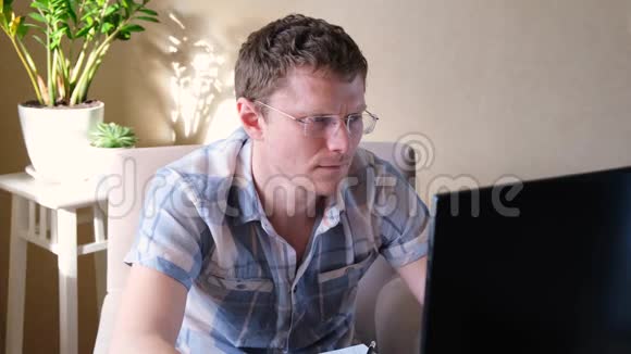 程序员在家工作远程家庭办公室一个戴眼镜的人看着显示器远程工作概念视频的预览图
