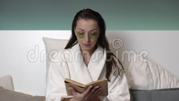 性感的女人穿着白色外套脸上贴着补丁睡觉前看书视频的预览图