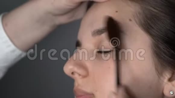 为坐在工作室的美丽而华丽的女人化妆的过程化妆师化妆视频的预览图