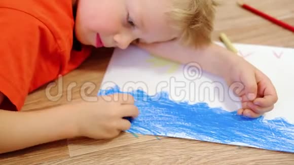 4k家里的孩子闭上小金发男孩的双手在地上画着黄色的太阳和蓝色的大海视频的预览图