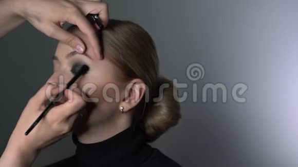 化妆师为美容工作室的年轻女性制作专业化妆化妆师让化妆师的眼睛光滑视频的预览图