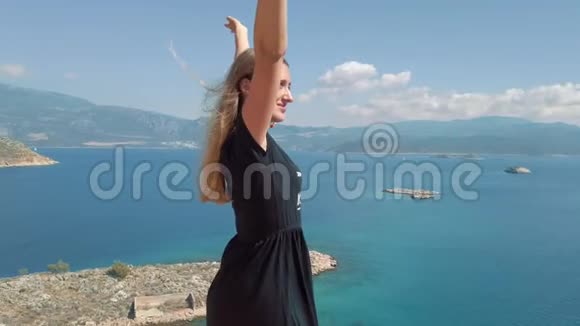 穿裙子的女人站在海边的悬崖边上视频的预览图