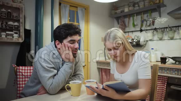 年轻夫妇喝茶讨论一本关于厨房的书视频的预览图