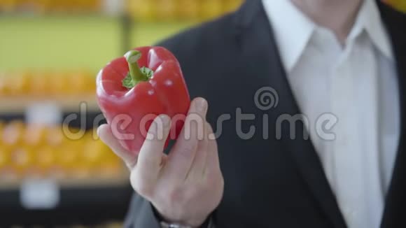 在杂货店里一只雄性白种人手拿着红色鲜椒的特写镜头无法辨认的人表现出素食视频的预览图