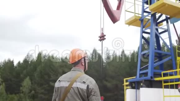 油田技术工人监督原油生产现场工业油泵千斤顶工作和抽采原油视频的预览图
