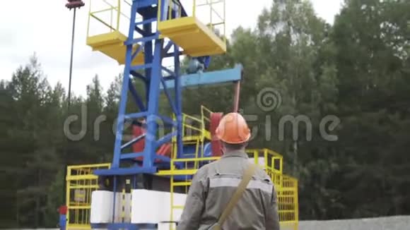 油田技术工人监督原油生产现场的抽油机工业油泵千斤顶工作视频的预览图