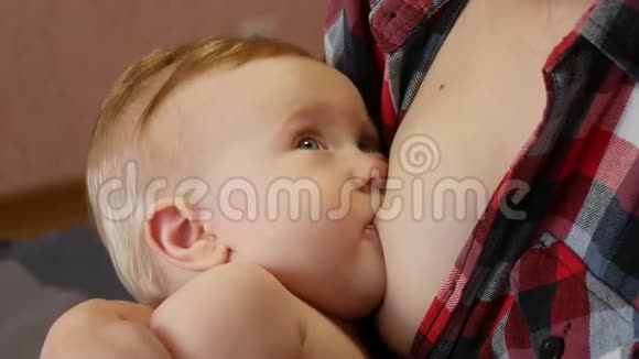 可爱的小婴儿用蓝眼睛和金发哺乳视频的预览图