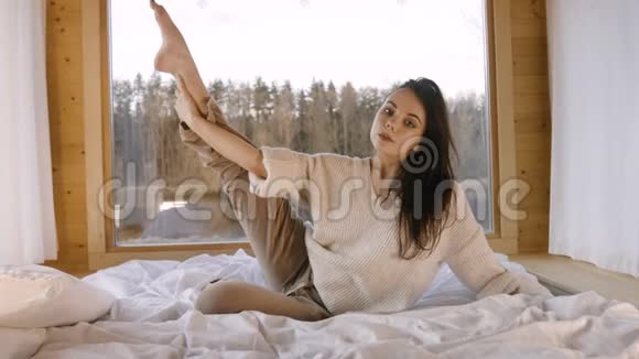 一个长头发的女孩在平房里的床上伸腿视频的预览图