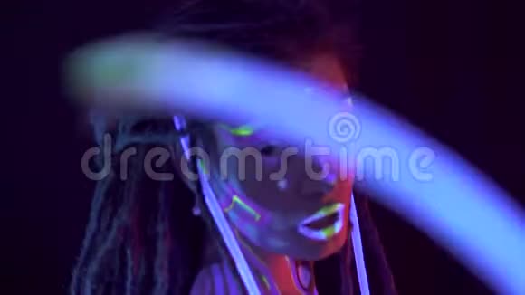 一个女孩的可怕的肖像在霓虹灯uf光模特儿跳舞的时候带着迷幻化妆的发光管艺术视频的预览图