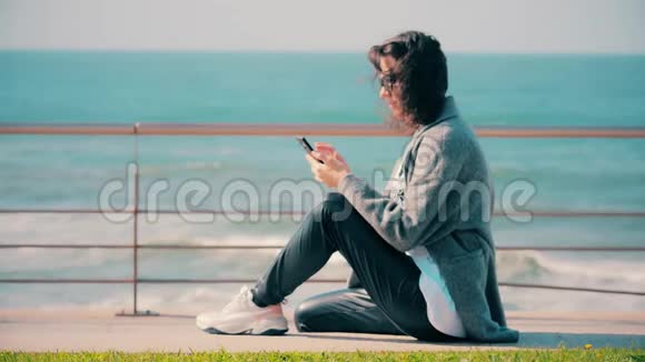 布鲁内特女孩在她的手机上读或写短信视频的预览图