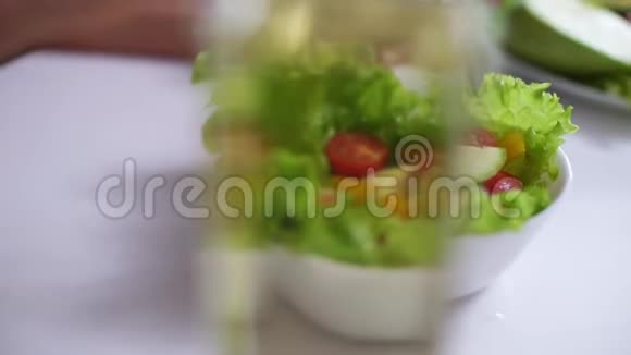 女人手把新鲜蔬菜沙拉混合在沙拉碗使用叉子特写视频的预览图