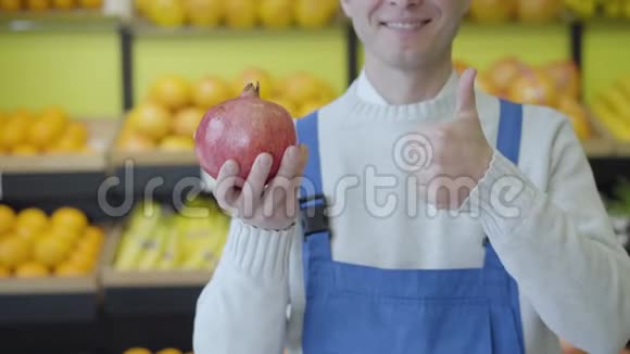 一个性格开朗不知名的白种人穿着蓝色的工作服手里拿着石榴朝上快乐的工人摆姿势视频的预览图