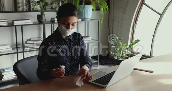 印度女商人戴着口罩用消毒液消毒笔记本电脑键盘视频的预览图