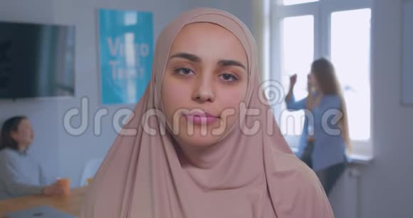 一位年轻美丽谦虚悲伤的穆斯林女孩在头巾办公室背景下的特写肖像视频的预览图