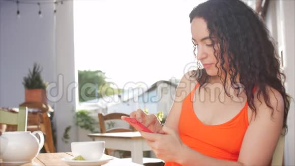 年轻女孩或妇女在咖啡馆喝咖啡在社交媒体上发短信享受移动技术视频的预览图