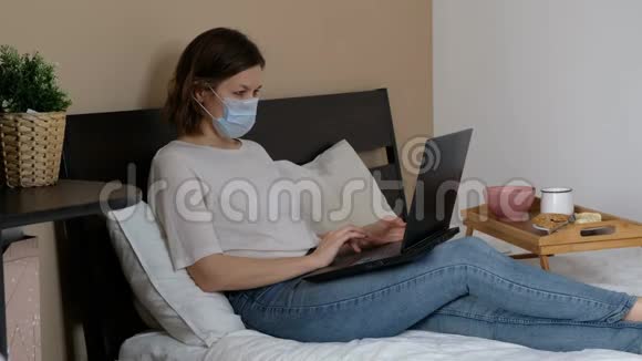 戴医疗口罩的妇女在家工作携带笔记本电脑同时检疫冠状病毒视频的预览图