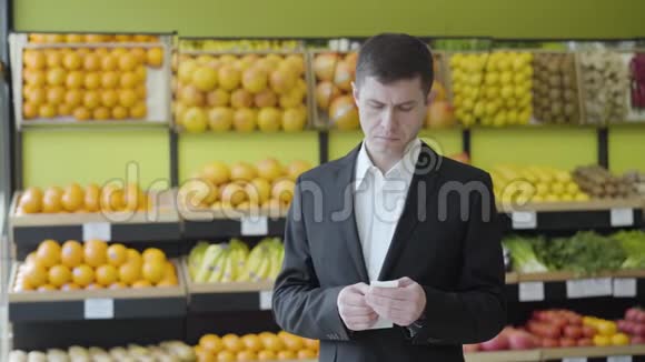 在杂货店里查看账单的白人成年人的正面表情很惊讶一幅严肃男人的画像视频的预览图