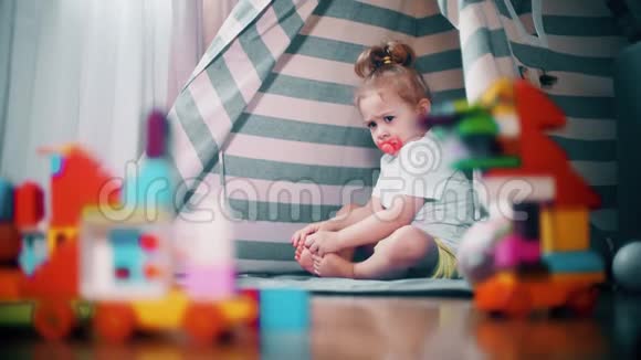 不高兴的皱着眉头的女婴坐在玩具帐篷在家里自我隔离概念视频的预览图