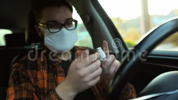 戴面具的人坐在车里消毒手COVID19视频的预览图