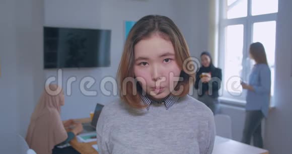 背景上一位年轻美丽害羞谦虚的亚洲办公室女孩的肖像视频的预览图