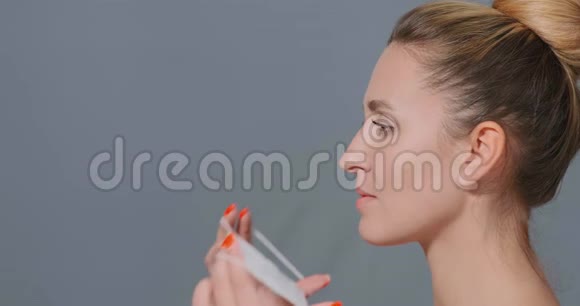 年轻女子把白色一次性面具戴在脸上视频的预览图