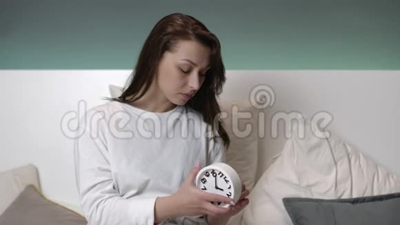 美丽的白种人女孩长发在床上设置闹钟上床睡觉视频的预览图
